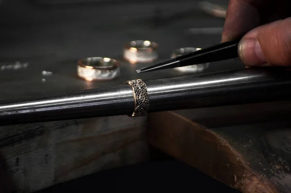 Close-up de mão de um ourives definindo o diamante no anel. Fabricação de jóias artesanais com ferramentas profissionais . — Fotografia de Stock