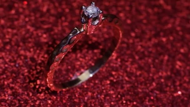 Bellissimo anello di fidanzamento dorato lucido con grande diamante gemma su sfondo rosso glitter. San Valentino presente. Proposta di matrimonio per il 14 febbraio — Video Stock