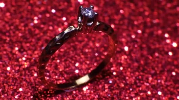 Красивое блестящее золотое обручальное кольцо с большим драгоценным бриллиантом на блестящем красном фоне. Подарок на День Святого Валентина. Предложение о браке на 14 февраля — стоковое видео