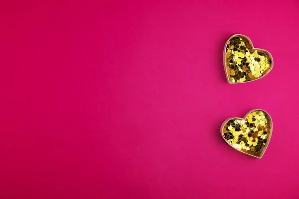 Dos corazones dorados con confeti sobre fondo rosa para el día de San Valentín. Espacio para el texto. Banner web o tarjeta de felicitación —  Fotos de Stock