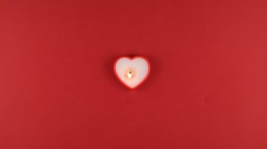 Sevgililer Günü için kırmızı arka planda kalp şeklinde yanan mum. 14 Şubat