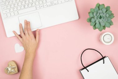 İnternetten Alışveriş Konsepti. Pembe arka planda telefonu ve laptopu olan kadın elleri. Üst görünüm, alanı kopyala.