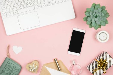 İnternetten Alışveriş Konsepti. Pembe arka planda telefonu ve laptopu olan kadın elleri. Üst görünüm, alanı kopyala.