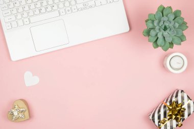 Pembe arka planda ofis aksesuarları olan kadın ofis masası. Kadın çalışma alanı sulu, mum ve kozmetik ile.