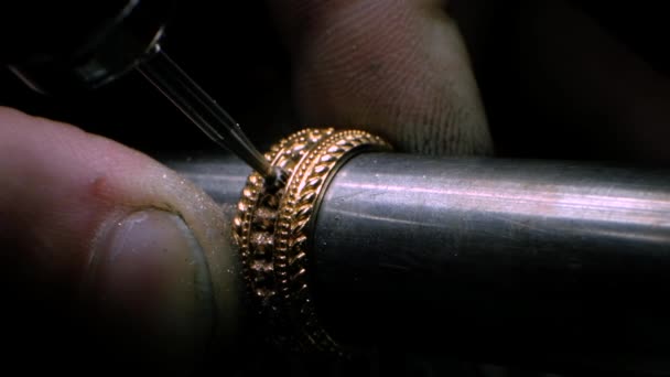 Goldsmith met behulp van een boorgereedschap om een gat te maken in de gouden ring. Juwelier boort een gat voor het plaatsen van een edelsteen. — Stockvideo