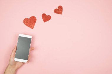  Akıllı telefon, elinde boş ekran ve eski ahşap masada kalpler.