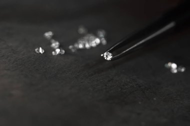 Diamond in tweezers. Craft jewelery, professional tools. Ring repairing. Macro shot. 