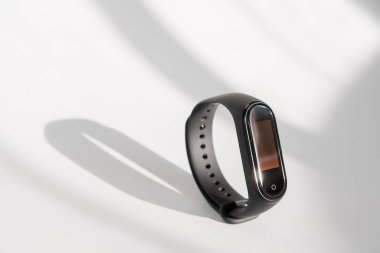 Akıllı fitness izleyicisi beyaz sabah ışığı arka planında izole edilmiş. Spor bileziği. Fitness bandı izleyici çalıştırıyor. Siyah fitness saati.