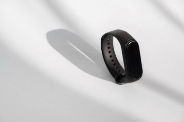 Akıllı fitness izleyicisi beyaz sabah ışığı arka planında izole edilmiş. Spor bileziği. Fitness bandı izleyici çalıştırıyor. Siyah fitness saati.