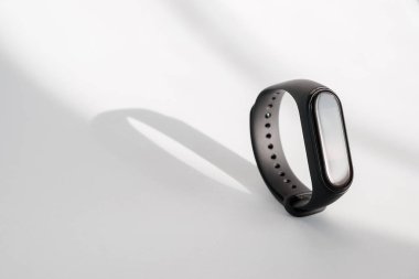 Akıllı fitness izleyicisi beyaz sabah ışığı arka planında izole edilmiş. Spor bileziği. Fitness bandı izleyici çalıştırıyor. Siyah fitness saati.