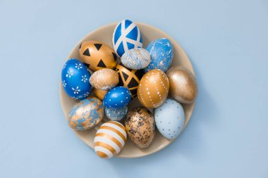Mavi arka planda izole edilmiş gri tabakta süslü Paskalya altınlı yumurtaları. Paskalya bayramı modası. Mesaj için fotokopi alanı olan mutlu Paskalyalar. Asgari paskalya kavramı