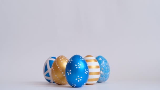 Le uova rotolano sul tavolo bianco, si picchiano a vicenda. Uova decorate d'oro Pasqua isolate su sfondo bianco. Concetto pasquale minimo. Buona Pasqua card . — Video Stock