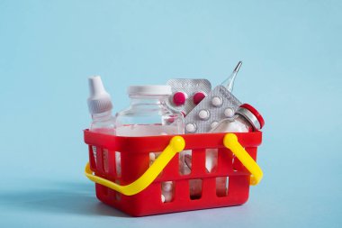 İnternetten ilaç alıp satmak. Mavi arka planda alışveriş sepetinde çeşitli kapsüller, tabletler ve ilaçlar var. Sağlık, sağlık sigortası ve ilaç şirketi için yaratıcı bir fikir