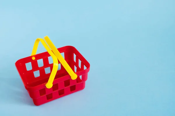 Röd tom leksak plast shopping korg isolerad på blå bakgrund. Försäljning och shopping koncept. Kopiera utrymme — Stockfoto