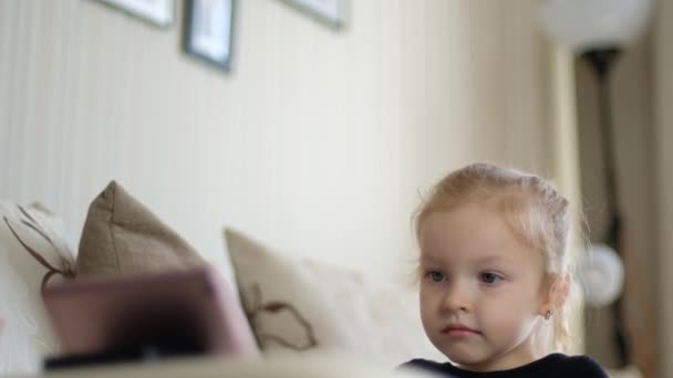 Uczenie się na odległość, edukacja online dla dzieci. Mała dziewczynka uczy się w domu przed smartfonem. Dzieci oglądają kreskówki, dzieci uzależnienie od komputerów, kontrolę rodzicielską. Kwarantanna w domu — Wideo stockowe