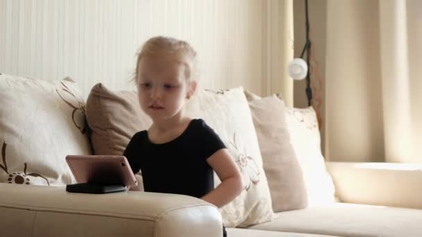 Educación a distancia, educación en línea para niños. Niña estudiando en casa delante del smartphone. Niño viendo dibujos animados en línea, adicción a la computadora de los niños, control parental. Cuarentena en casa — Vídeos de Stock