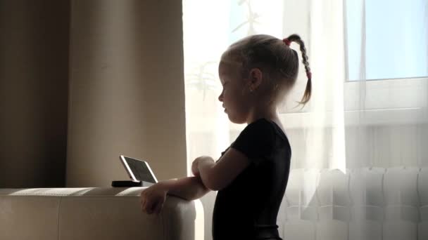 Enseignement à distance, éducation en ligne pour les enfants. Petite fille étudiant à la maison devant le smartphone. Enfant regardant des dessins animés en ligne, dépendance à l'ordinateur des enfants, contrôle parental. La quarantaine à domicile — Video