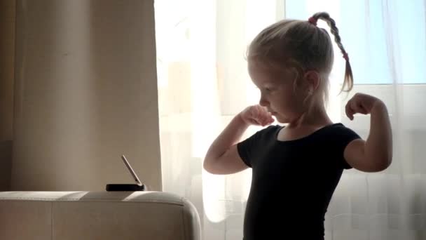 Uzaktan öğrenme, çocuklar için online eğitim. Çalışan küçük bir kız, akıllı telefonun önünde dans etmeyi öğreniyor. Evde karantina — Stok video