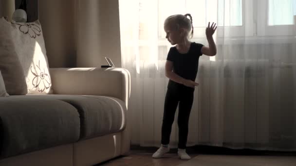 Fernunterricht, Online-Bildung für Kinder. Kleines Mädchen lernt zu Hause vor dem Smartphone tanzen. Quarantäne zu Hause — Stockvideo