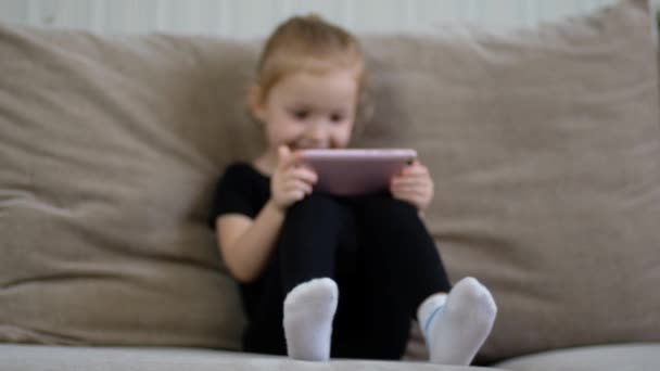 Educación a distancia, educación en línea para niños. Niña estudiando en casa delante del smartphone. Niño viendo dibujos animados en línea, adicción a la computadora de los niños, control parental. Cuarentena en casa — Vídeo de stock