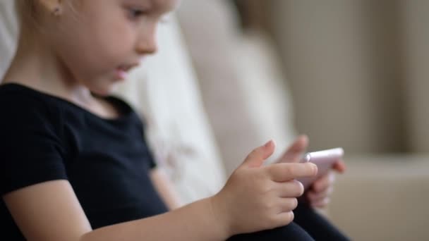 Fernunterricht, Online-Bildung für Kinder. Kleines Mädchen beim Lernen zu Hause vor dem Smartphone. Kinder gucken Online-Cartoons, Kinder Computersucht, elterliche Kontrolle. Quarantäne zu Hause — Stockvideo