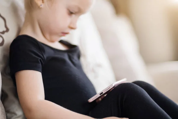 Apprendimento a distanza, educazione online per bambini. Ragazza felice tenendo smartphone in mano. Bambino che guarda cartoni animati online, bambini dipendenza dal computer, controllo parentale. Quarantena a casa — Foto Stock