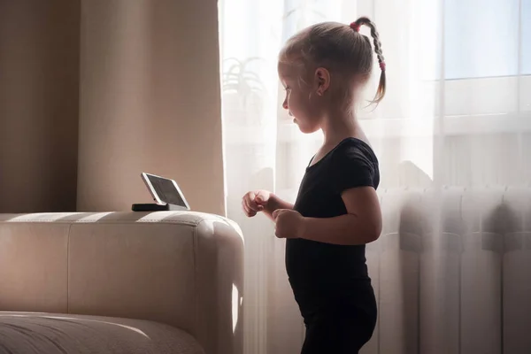 Educación a distancia, educación en línea para niños. Niña estudiando en casa delante del smartphone. Niño viendo dibujos animados en línea, adicción a la computadora de los niños, control parental. Cuarentena en casa —  Fotos de Stock