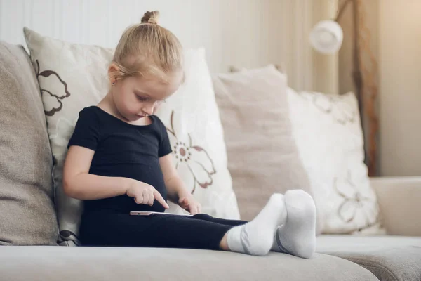 Bambino che guarda cartoni animati online, fogliame e strisciare. Apprendimento a distanza, educazione online per bambini. Bambina che studia a casa davanti allo smartphone. Quarantena a casa — Foto Stock