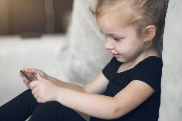 Apprendimento a distanza, educazione online per bambini. Bambina che studia a casa davanti allo smartphone. Bambino che guarda cartoni animati online, bambini dipendenza dal computer, controllo parentale. Quarantena a casa — Foto Stock