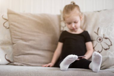 Uzaktan öğrenme, çocuklar için online eğitim. Küçük kız akıllı telefonun önünde evde ders çalışıyor. Çocuk online çizgi film izliyor, çocuk bilgisayar bağımlısı, ebeveyn kontrolü. Evde karantina