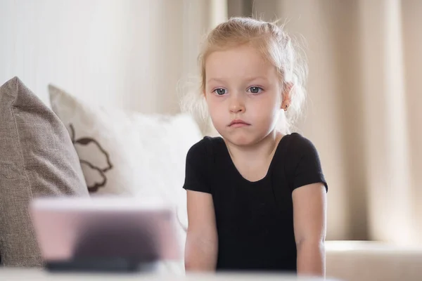 Niña triste y cansada estudiando en casa delante del smartphone. Educación a distancia, educación en línea para niños. Adicción a la computadora infantil, control parental. Cuarentena en casa —  Fotos de Stock