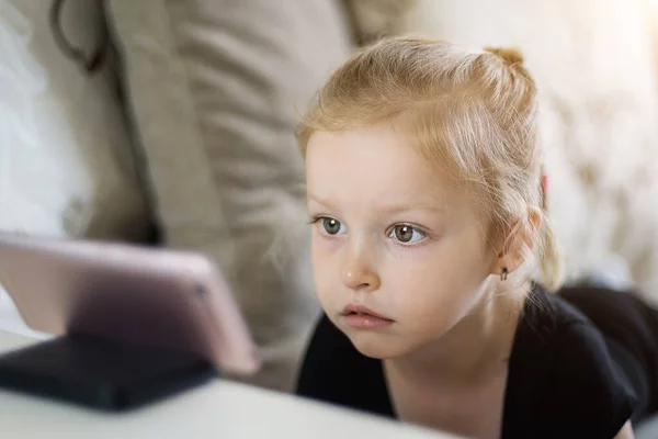 Távolságtanulás, online oktatás gyerekeknek. A kislány otthon tanul az okostelefon előtt. Gyerek online rajzfilmeket néz, gyerekek számítógép-függőség, szülői felügyelet. Karantén otthon — Stock Fotó