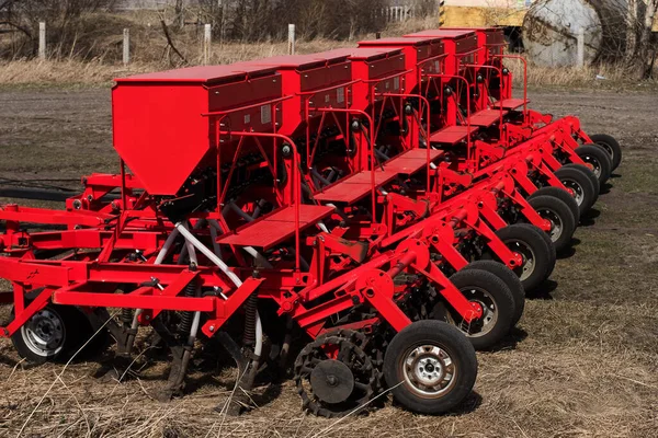 Máquina de sementes de semeadura moderna. Semeadura de trator de agricultores. Arado de combinação vermelho. Semeando culturas em campos agrícolas na primavera . — Fotografia de Stock