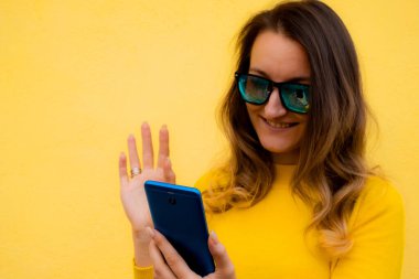 Güzel, güzel, mutlu bir kadın akıllı telefon kullanıyor. Şaşırmış bir kız cep telefonuyla mesaj atıyor. Teknoloji, bağlantı, iletişim, sosyal medya kavramı