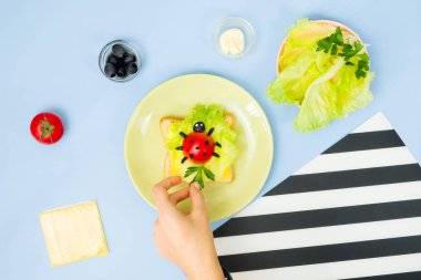 Çocuklar için eğlenceli yemek sanatı. Mavi arka planda uğur böceği sandviçi. Evde çocuklara yaratıcı kahvaltı hazırlamayı. Adım adım talimat, yukarıdan görüş. Adım .