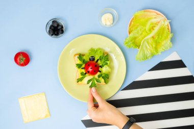 Çocuklar için eğlenceli yemek sanatı. Mavi arka planda uğur böceği sandviçi. Evde çocuklara yaratıcı kahvaltı hazırlamayı. Adım adım talimat, yukarıdan görüş. Adım .