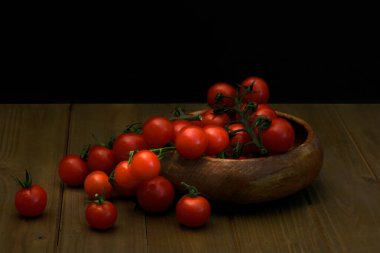 Siyah arka planda taze vişneli domatesler. Yan taraftan kesilmiş ve yarıya bölünmüş siyah arka planda. Yan taraftan ahşap tahtada yiyecek.