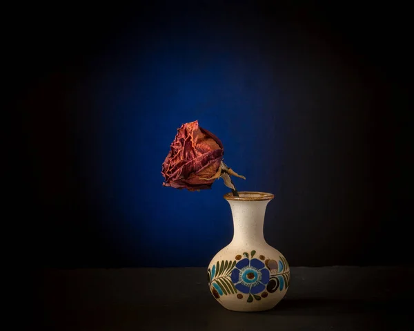 将枯死的 枯干的玫瑰放在陶瓷罐子里 在黑暗和蓝色的背景下展示静止的生命 时间的流逝 孤独和死亡的概念 — 图库照片