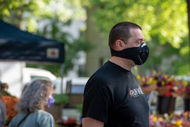 Davis, Kaliforniya, ABD. 8 Mayıs 2020. Beyaz, orta yaşlı erkek, çiftçi pazarında kapakçığı olan siyah bir maske takıyor..