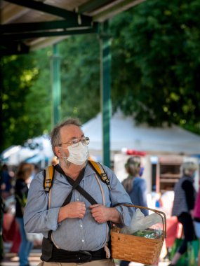 Davis, Kaliforniya, ABD. 8 Mayıs 2020. Kafkas erkek sebze dolu bir sepet taşıyor ve pazarda yüz maskesi takıyor.