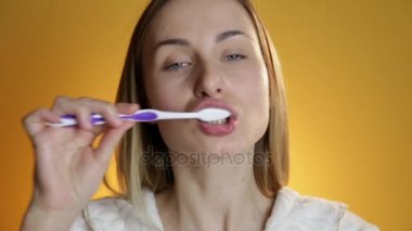 Dişlerini fırçalama ve sarı arka planı gülümseyen kadın