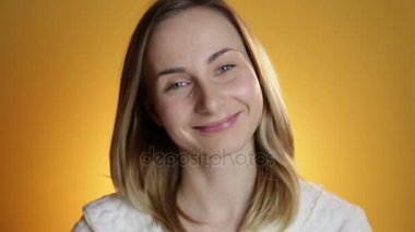 Genç ve güzel kadın mutlu kameraya sarı bir arka plan üzerinde seyir gülümseyen