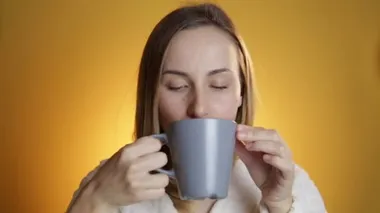 Sarı bir arka plan üzerinde bir kupa çay içme kadın