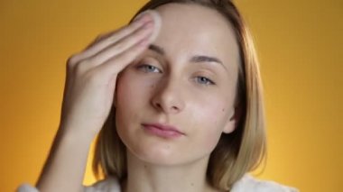 Kadın sarı bir arka plan üzerinde yüz temizleyici