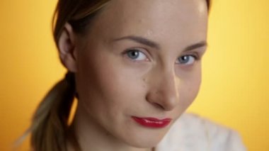 Açık sarı arka plan üzerinde kameraya bakıyor güzel gülümseyen kadın portresi