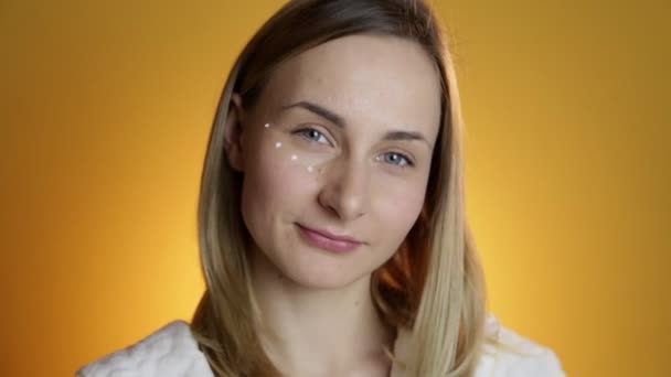 Крупный план портрета красивой женщины, наносящей крем на лицо — стоковое видео