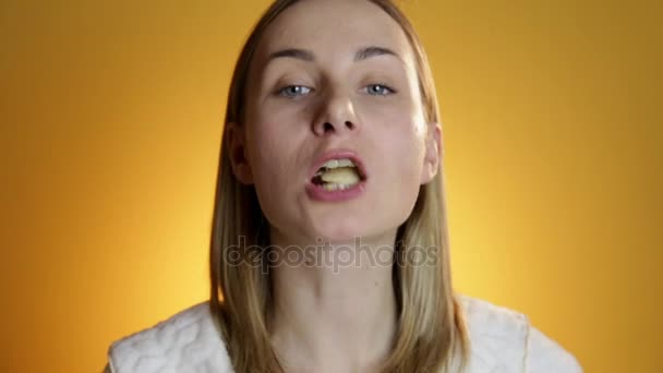 Jovem mulher comendo batatas fritas no fundo amarelo — Vídeo de Stock