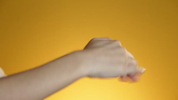 Young woman hands being smeared with white beauty cream on yellow background — Stock Video