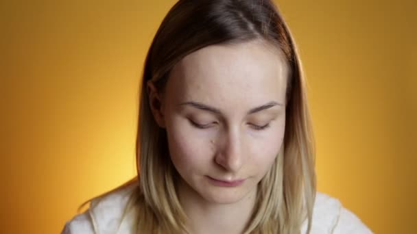 Blonde Frau spritzt ihr Gesicht gegen einen auf gelbem Hintergrund — Stockvideo