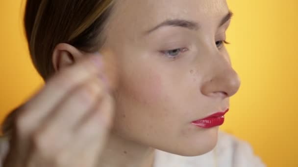 Vackra glad ung dam att lägga makeup på gul bakgrund — Stockvideo